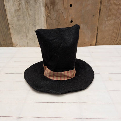 Black hat with plaid band on a wooden surface